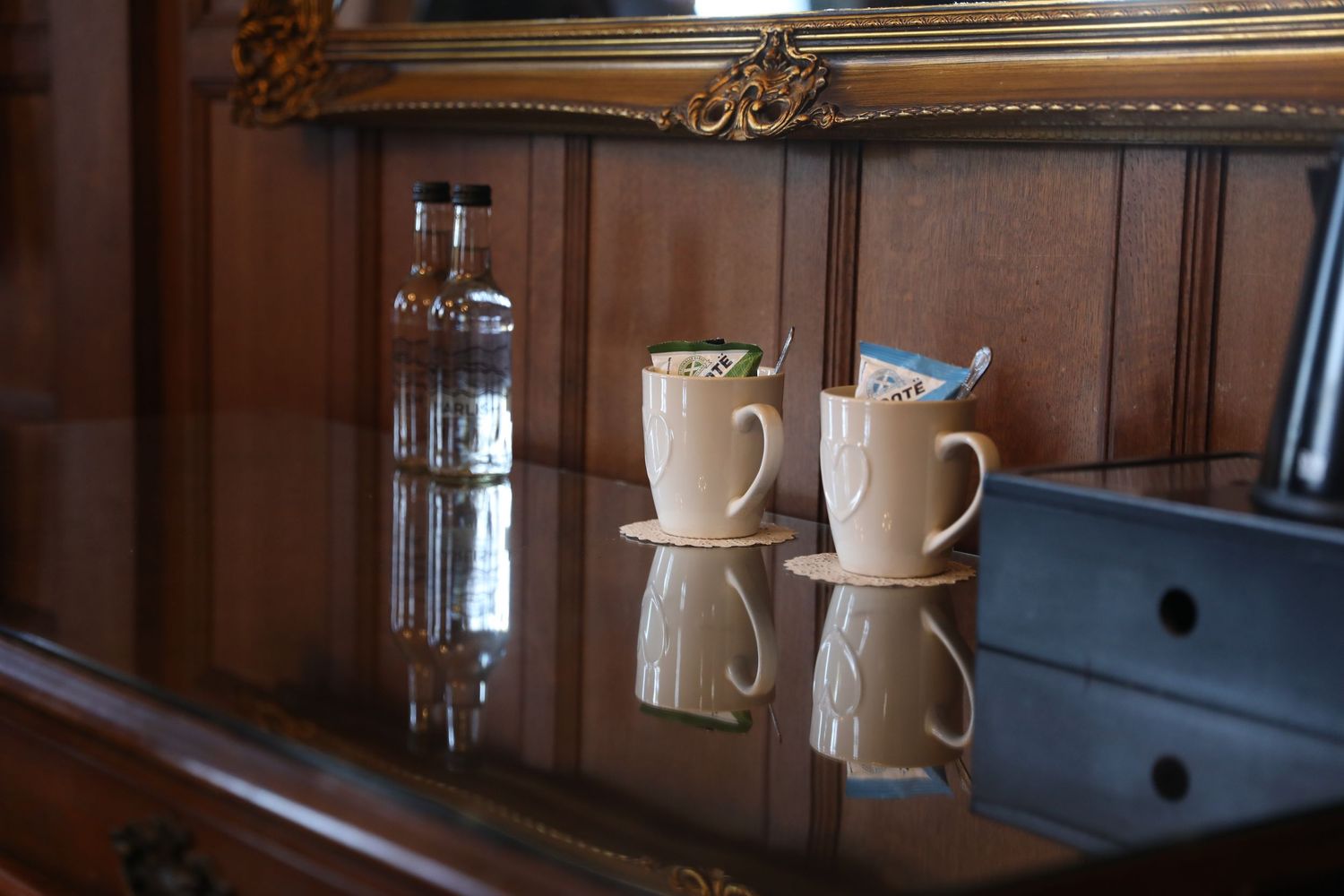 White ceramic coffee cups and mugs displayed on wooden shelves in a traditional kitchen interior.