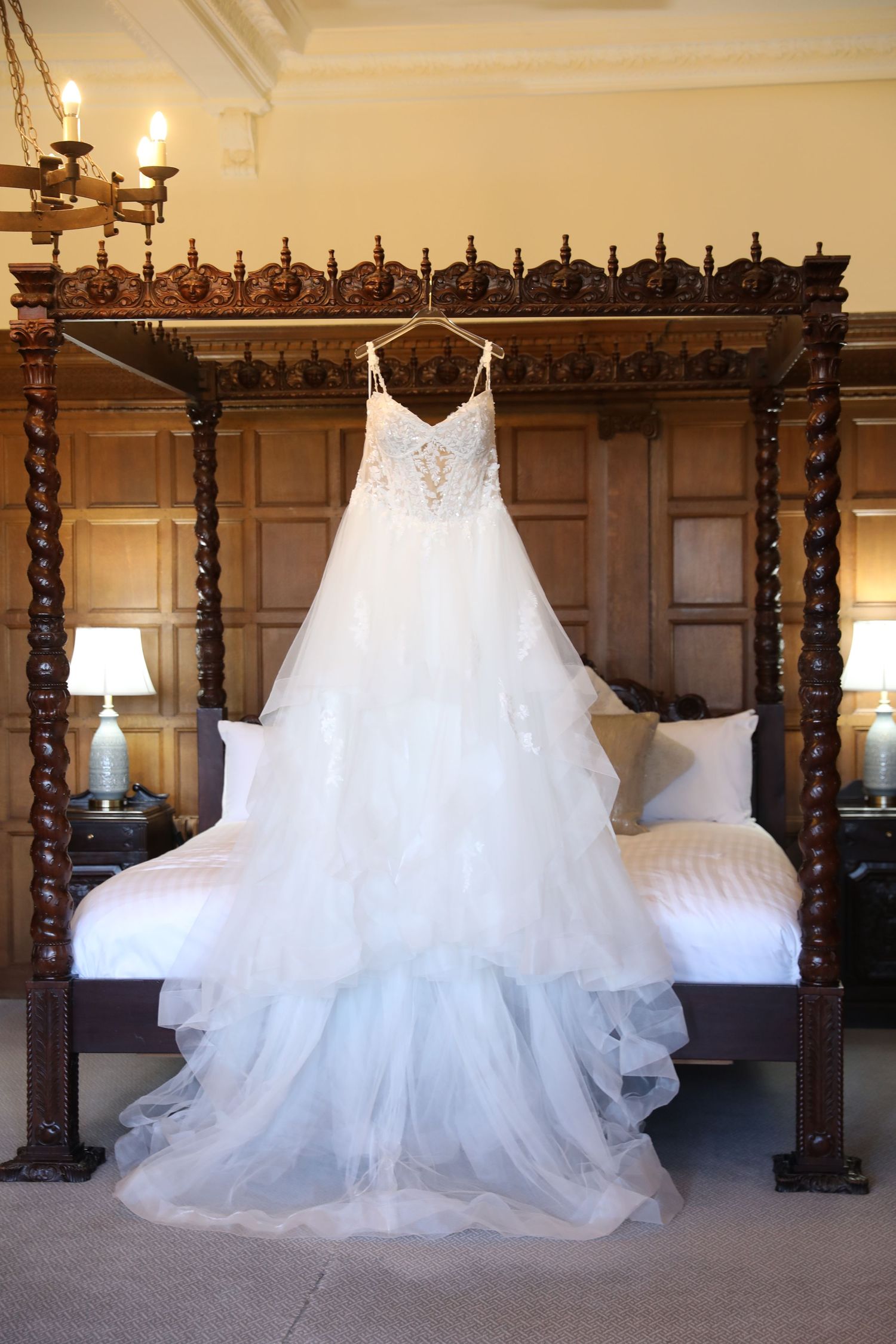 Multiple elegant white wedding dresses displayed in a row against dark wooden paneling in a bridal boutique.