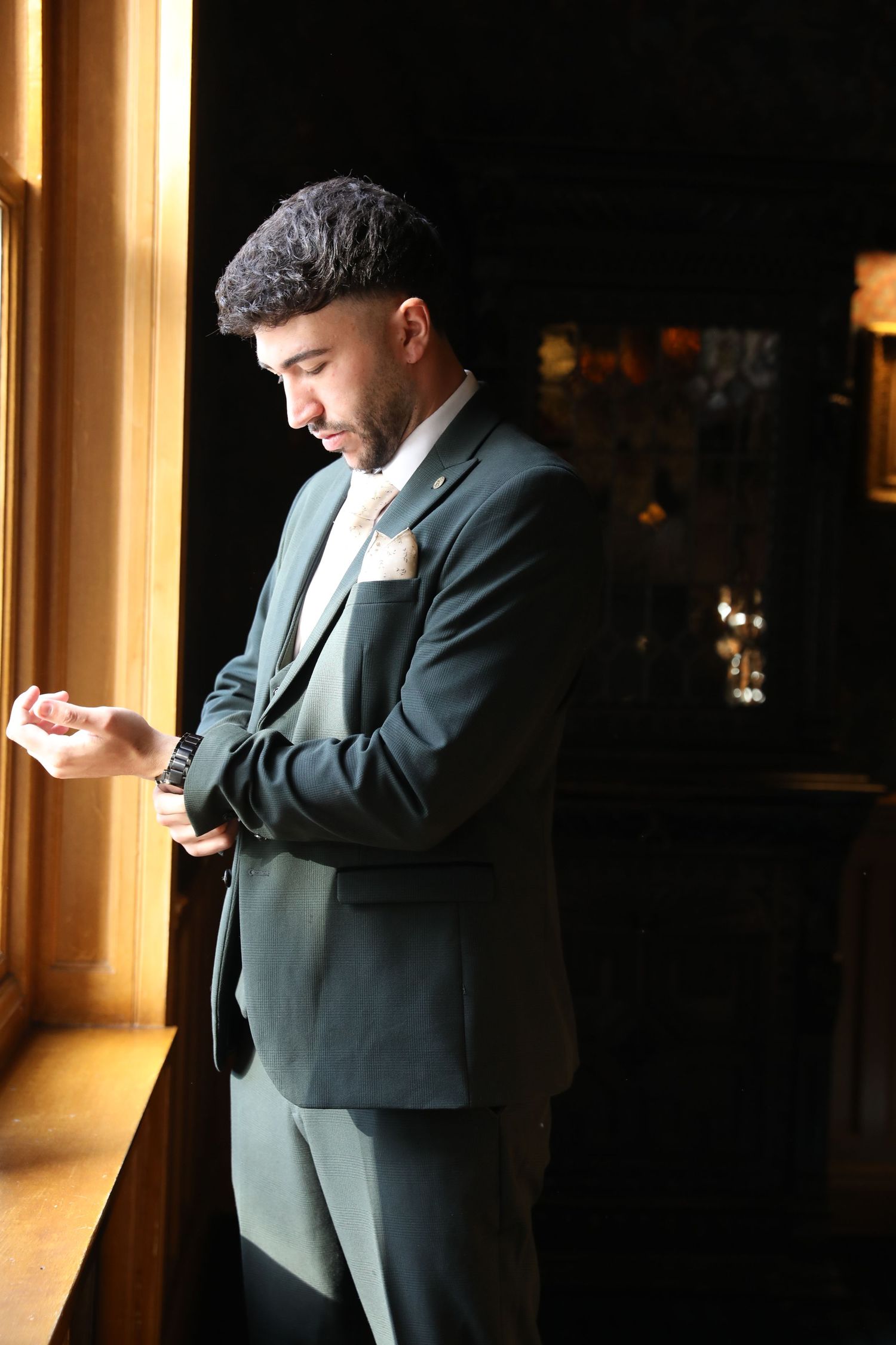 Person in a dark suit stands in dramatic lighting against a window, creating a silhouetted profile effect.