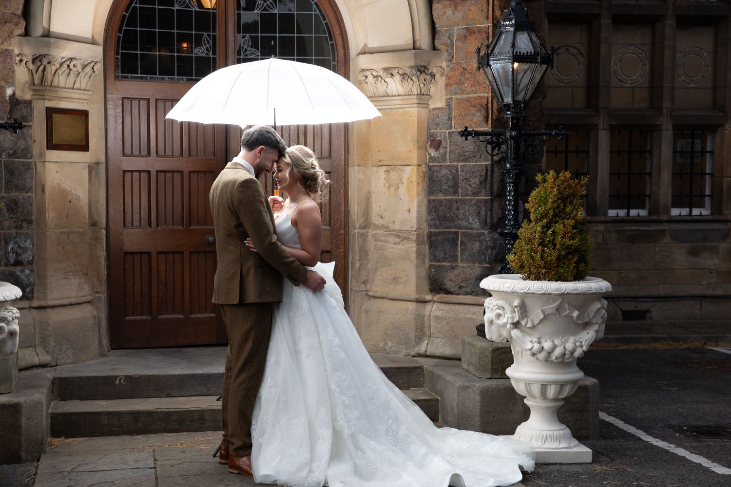 Wedding couple poses together in elegant archways of historic stone building with ornate architecture.