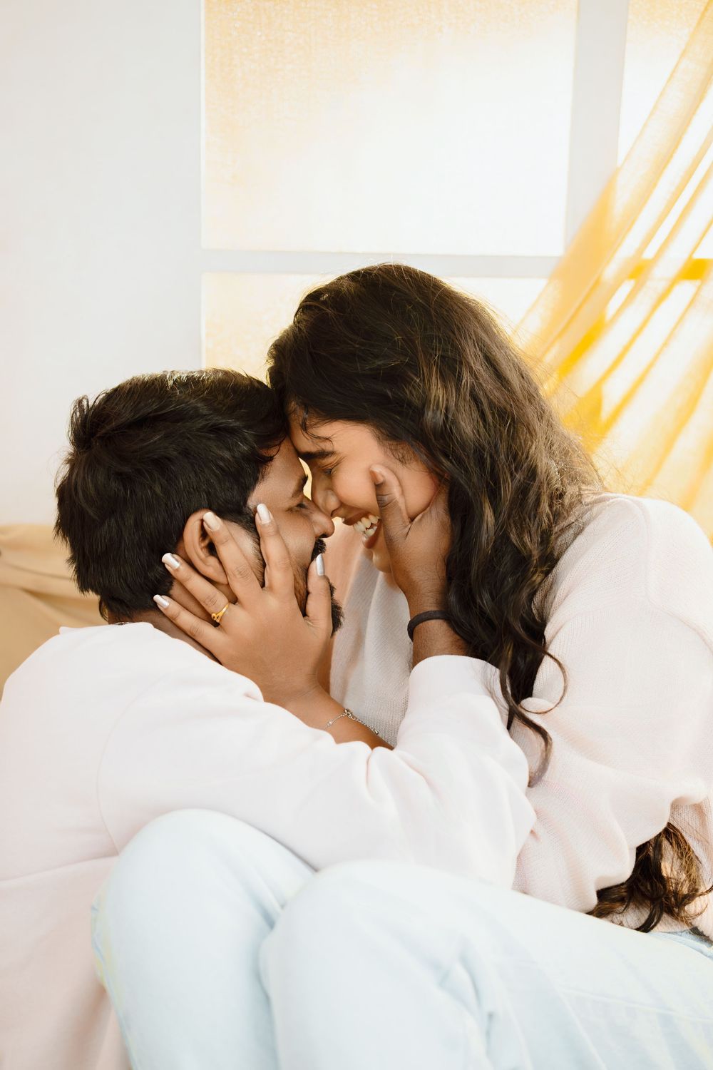 Romantic sequence of four photos showing a tender kiss between two people wearing white clothing.