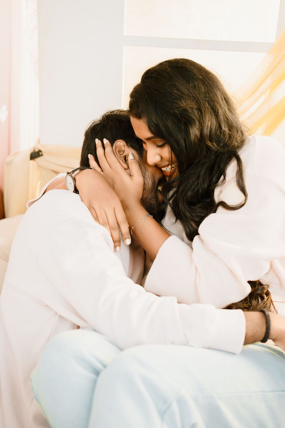 Two people in white shirts share an intimate embrace in a softly lit setting.