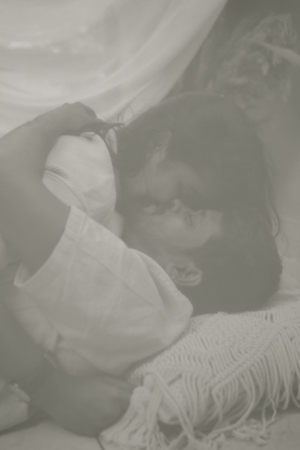 A couple shares an intimate black and white moment on textured fabric.