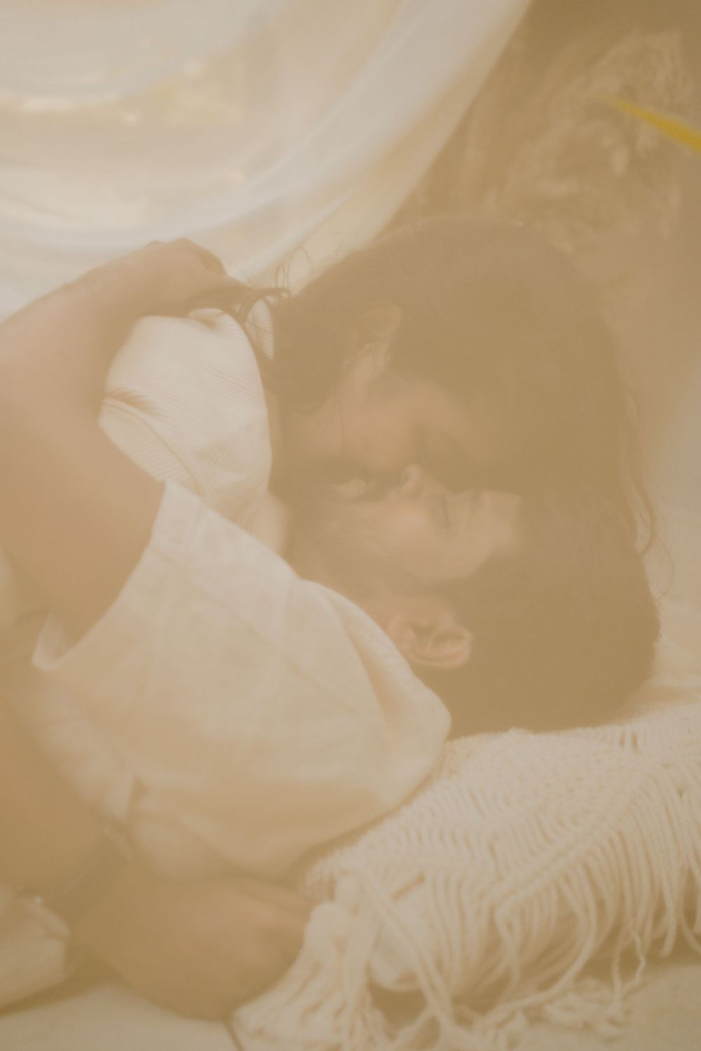 Intimate couple portrait with soft beige tones and delicate fabric textures.