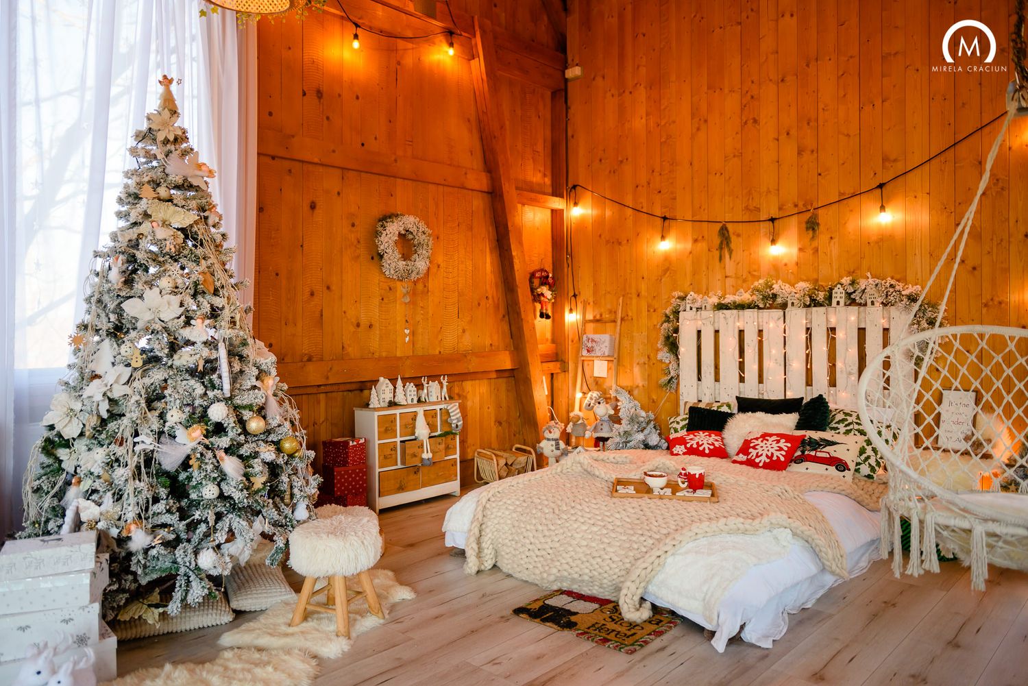Cozy wooden cabin interior decorated for Christmas with twinkling lights, flocked trees and festive holiday decor.
