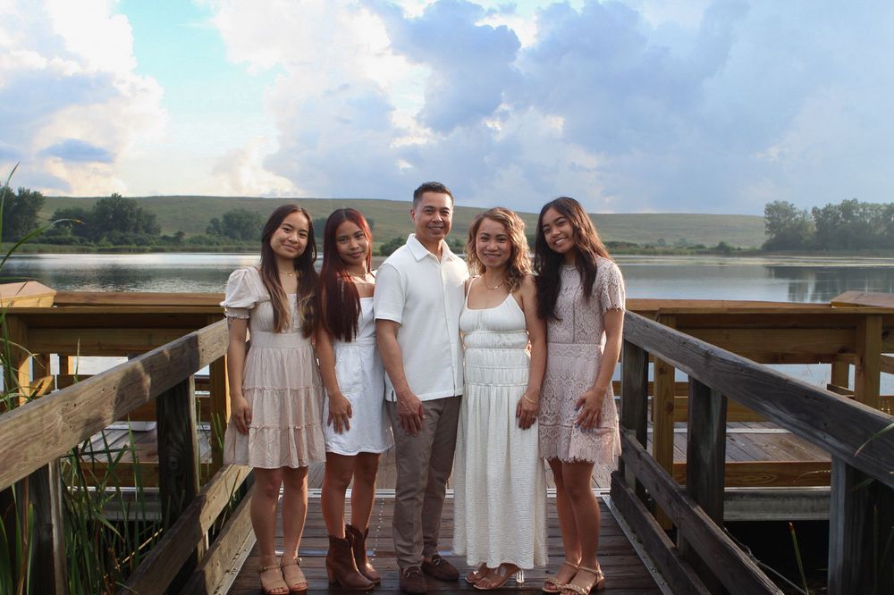 Group photo on a wooden dock overlooking a serene lake during golden hour.