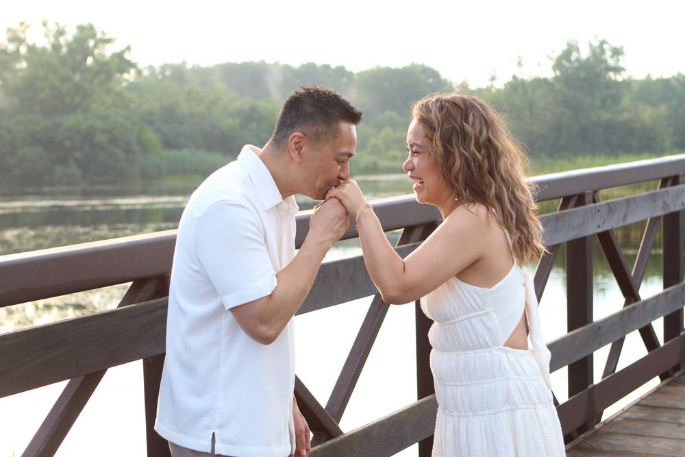Romantic couples photoshoot on a wooden bridge overlooking a peaceful lake.