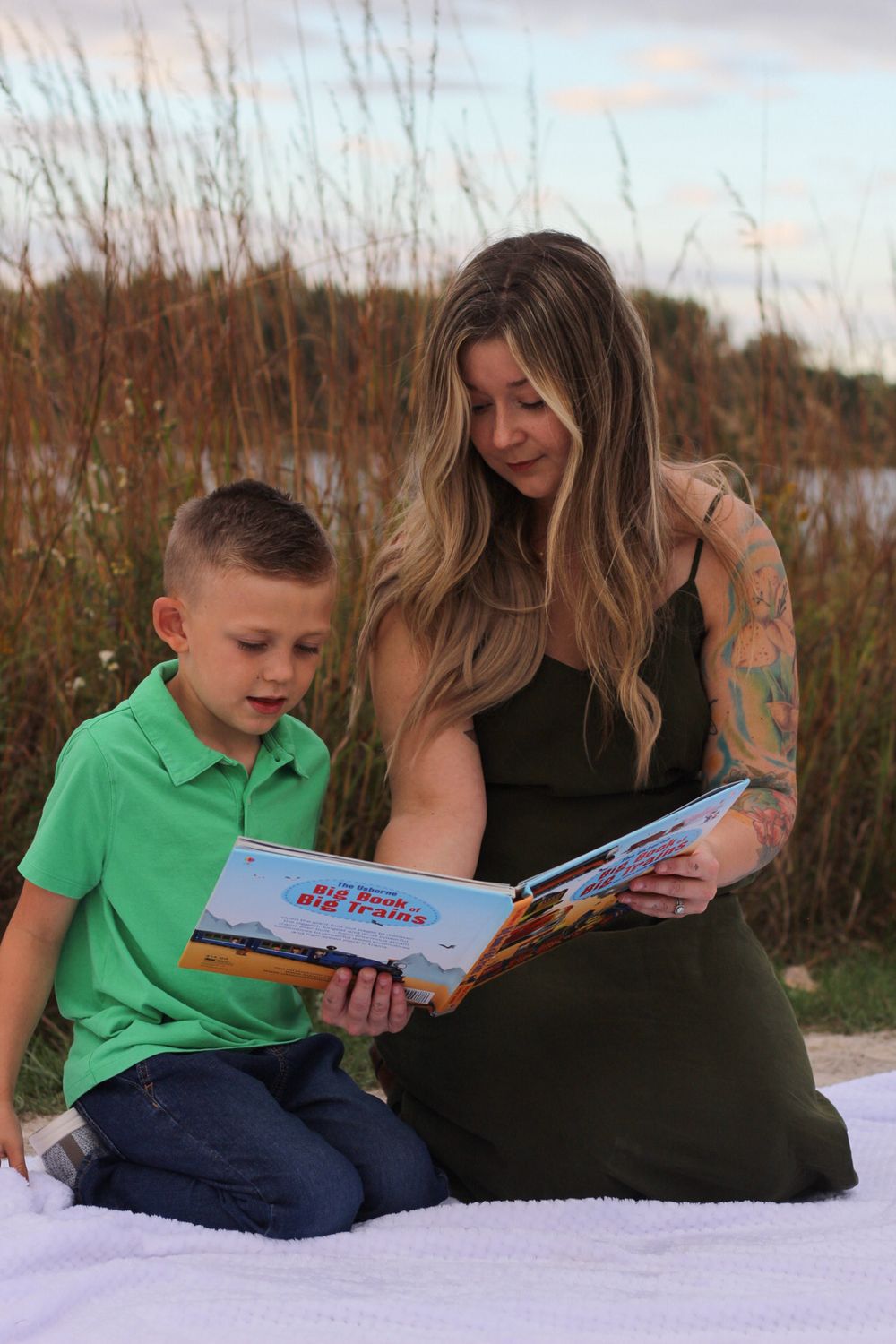 Reading time on the beach with a child in green polo shirt sharing a storybook.
