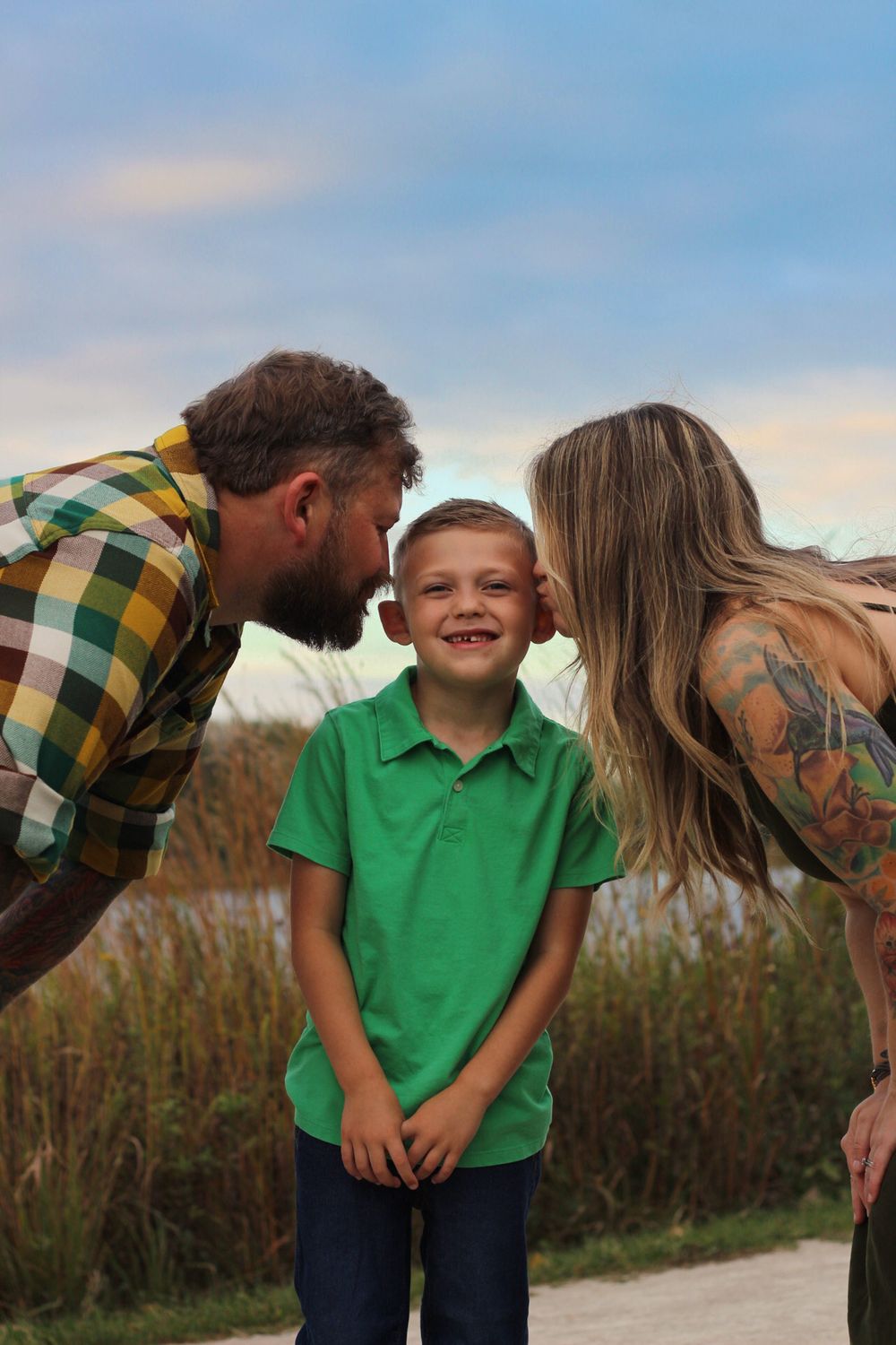 Playful family moment on beach path with child in bright green polo shirt.