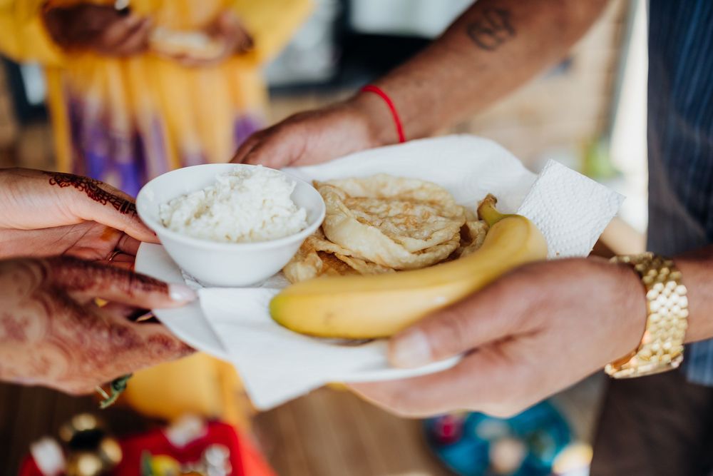 Hands passing plate of food with rice and flatbread at casual dining setting.