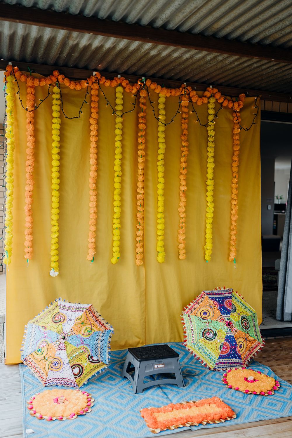 Colorful decorative umbrellas and hanging yellow and orange garlands create a festive wedding display.