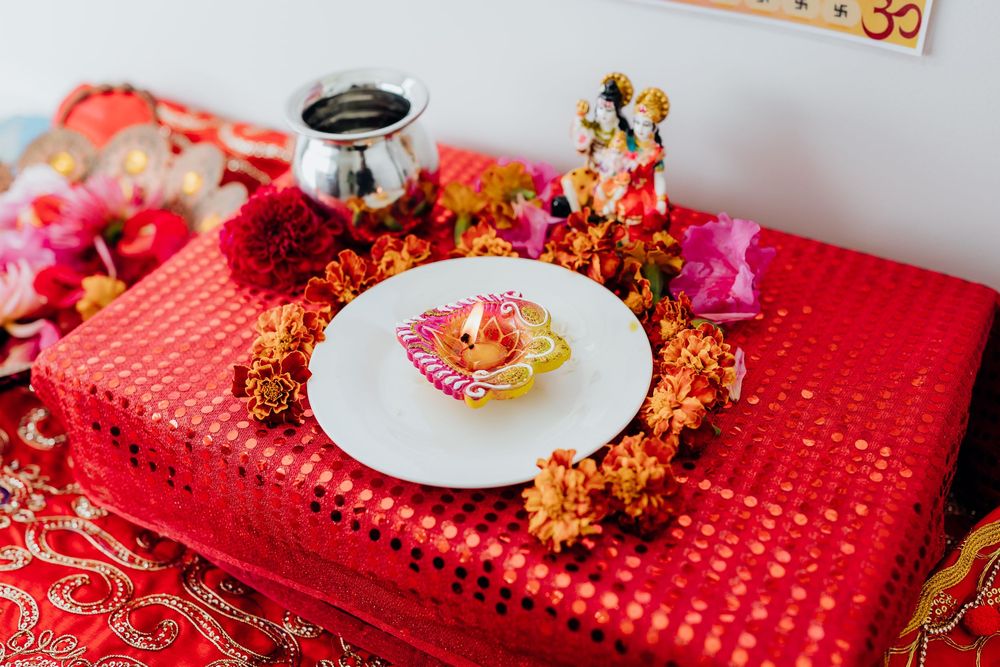 Colorful Indian wedding altar setup with red tablecloth and decorative plate arrangement.