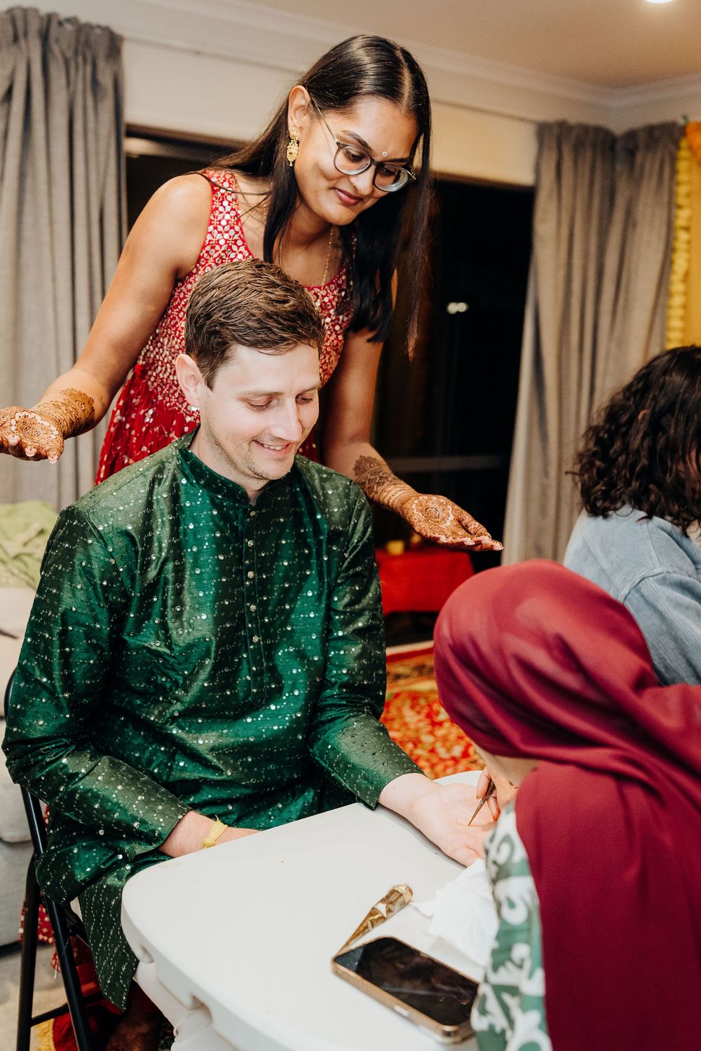 Wedding guests in traditional attire participate in cultural ceremony rituals indoors.