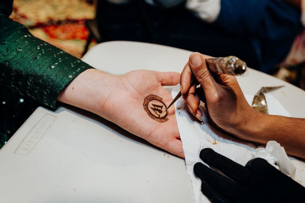 Hands shown during a traditional wedding ceremony ritual with henna decorations.