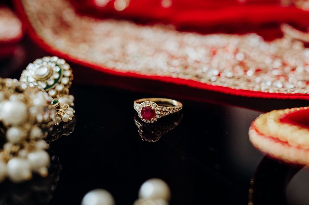 Close-up detail shot of wedding rings and pearl jewelry on red fabric.