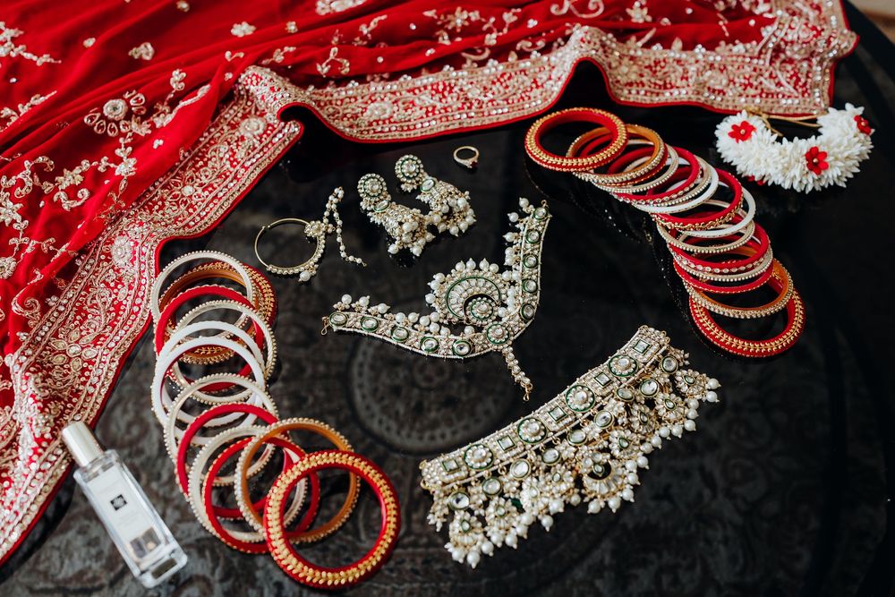 Traditional Indian wedding jewelry and accessories including red bangles and ornate silver pieces on black fabric.