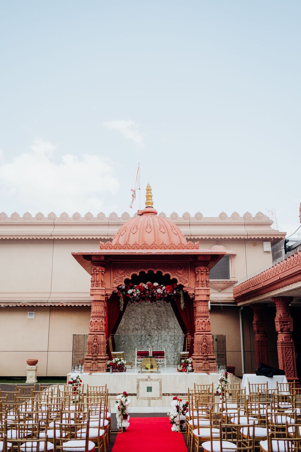 Traditional Indian wedding mandap with red and white decor and gold accents.