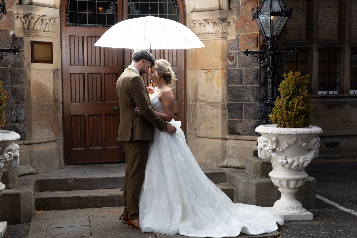 A couple in wedding attire shares a romantic moment under a lamp post in a charming stone courtyard.