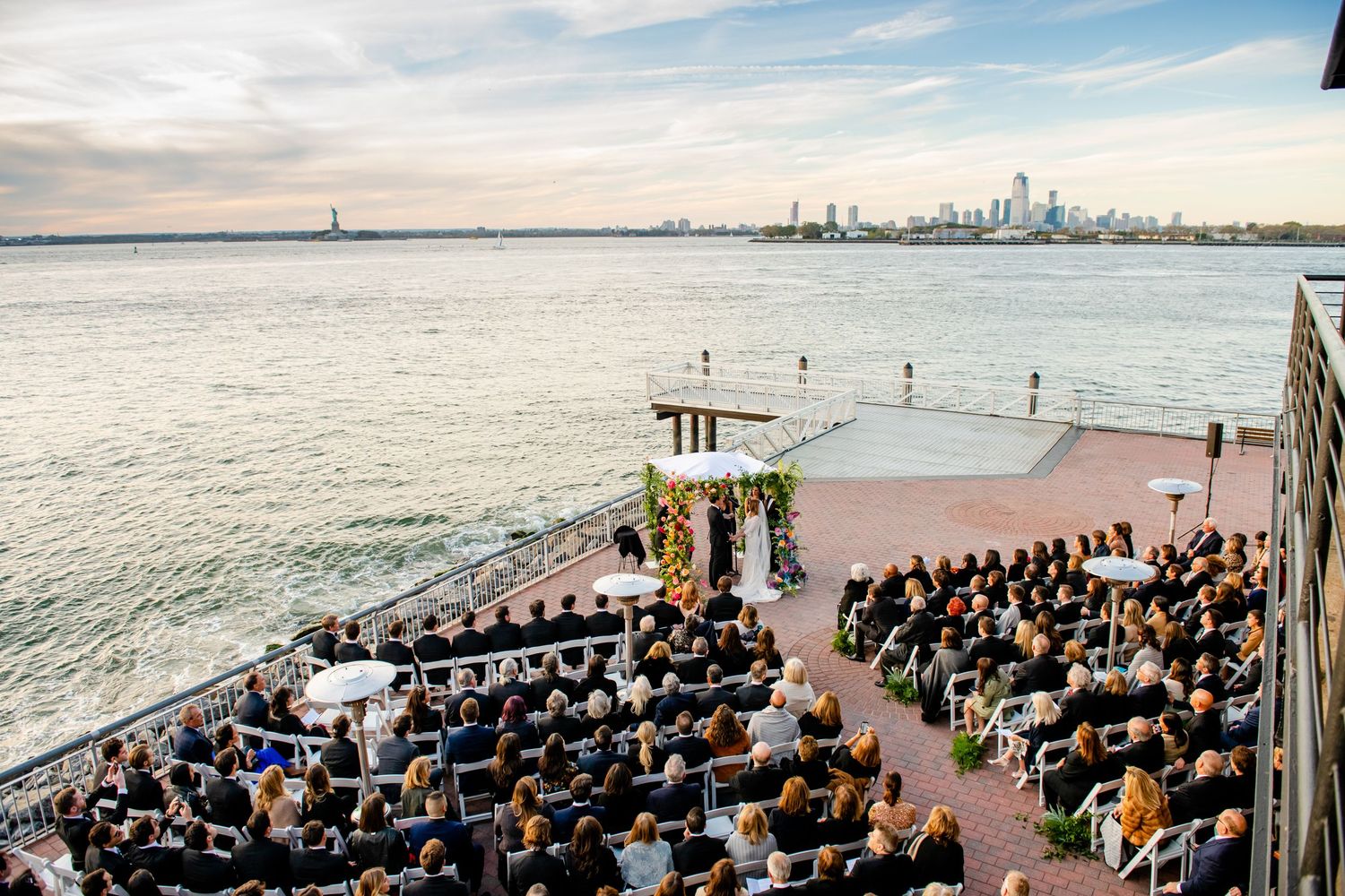 A waterfront wedding ceremony overlooking a city skyline across the water.