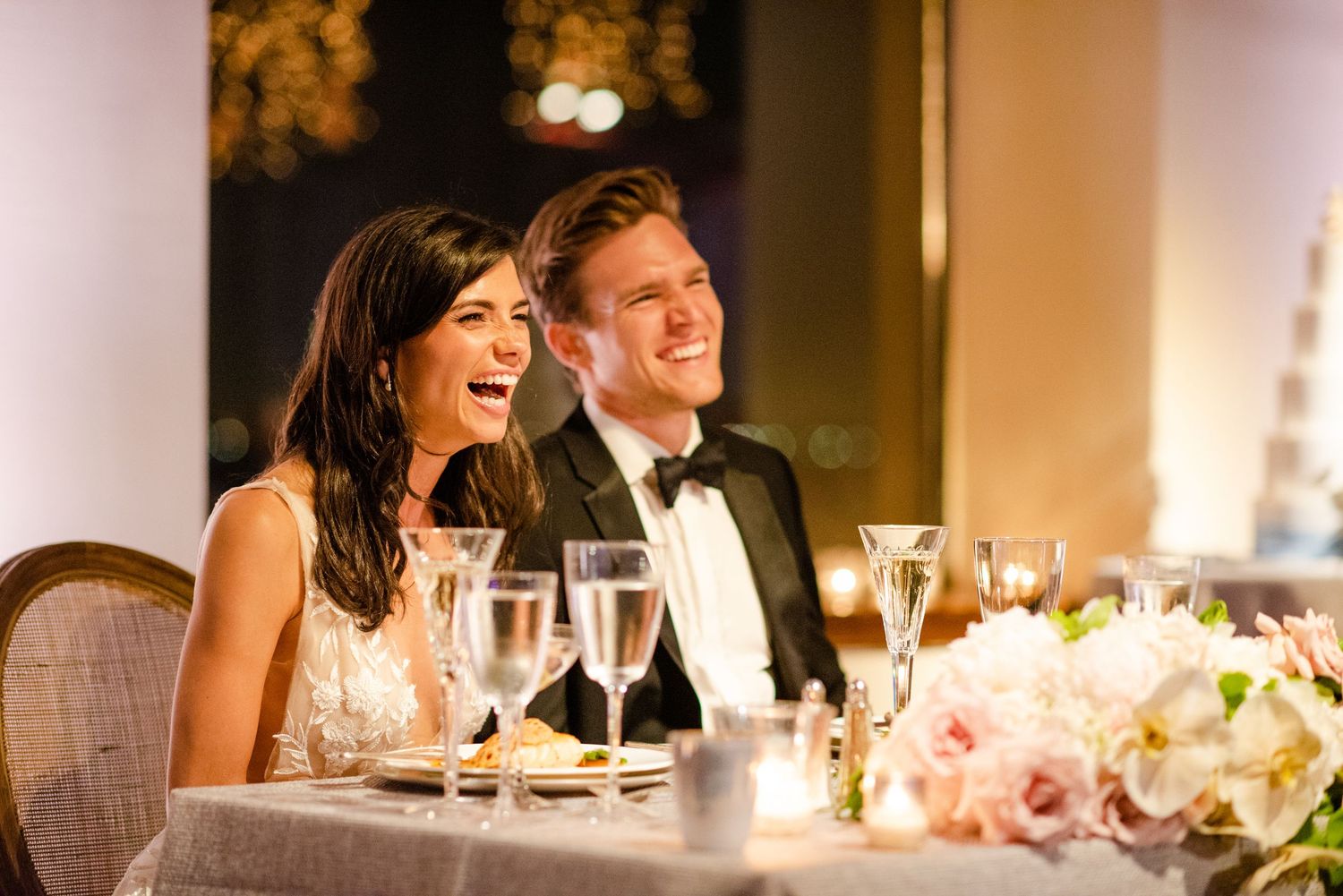 Elegant wedding reception dinner with table settings and soft lighting.