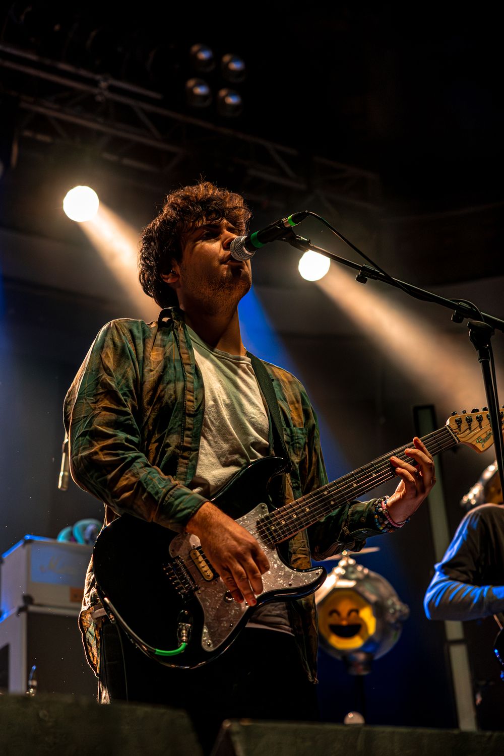 Musicians perform on stage with dramatic lighting and electric guitars during a live concert performance.