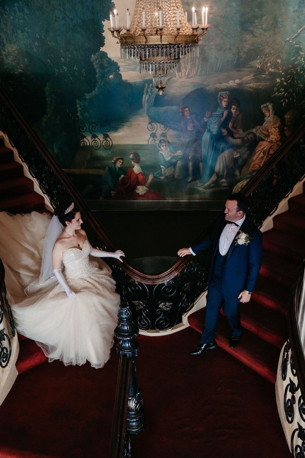 Dramatic dance scene with chandelier lighting and ornate decor in dark tones.