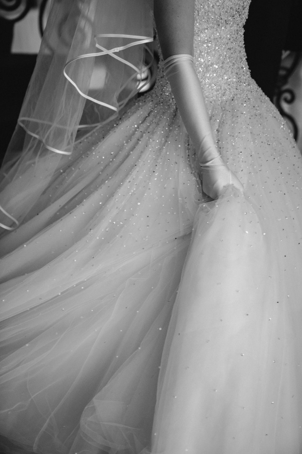 Close-up detail of a white wedding dress with sparkling tulle fabric and delicate beading embellishments.