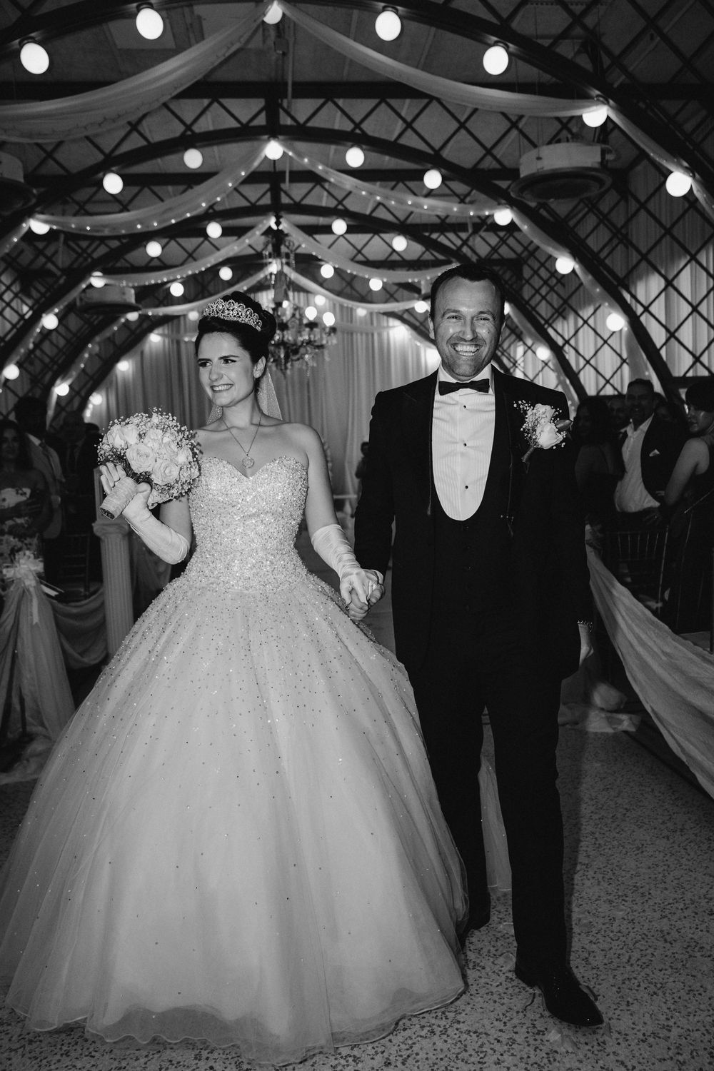 Wedding celebration under string lights with a dramatic ballgown dress.