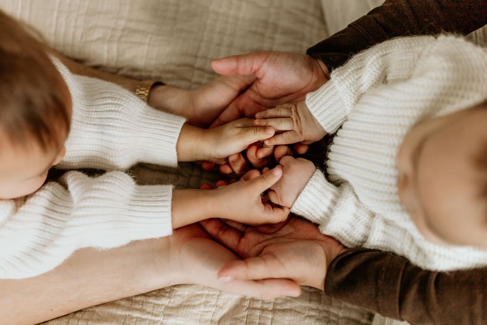A sequence of hands gently holding and intertwining in intimate gestures against a white fabric background.