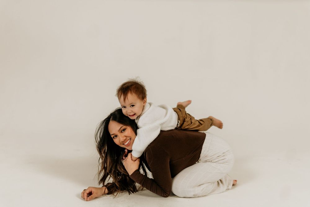 A series of four candid photos showing a person in a brown sweater and white pants lying down on a light background.