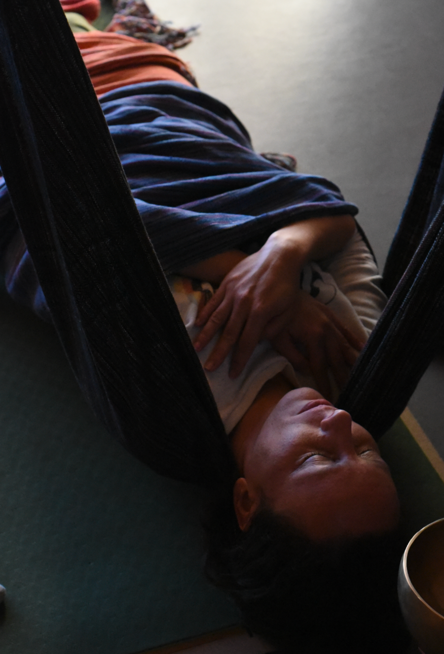 A person rests peacefully in a dark hammock with blue and orange fabric visible in the background.