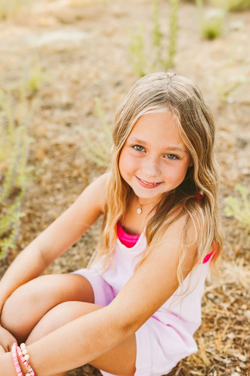 A casual summer portrait taken outdoors showing a bright smile and pink clothing against a natural background.