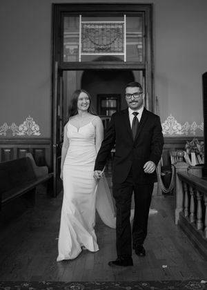 Black and white sequence showing a couple walking together in a historic building hallway.