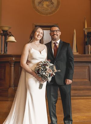 Wedding couple poses together in a classic ballroom with traditional architectural details.