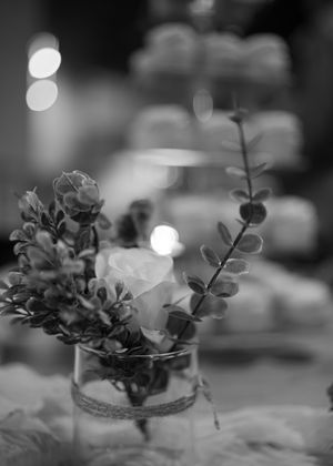 Black and white detail shot of floral centerpieces with soft bokeh lighting.