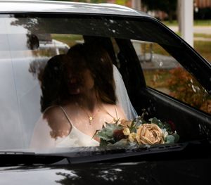 Side view through car window during wedding day preparations.
