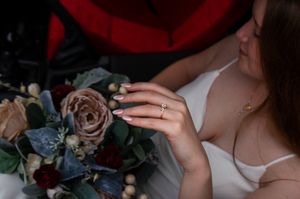 Wedding bouquet with dusty rose and burgundy flowers in car interior.