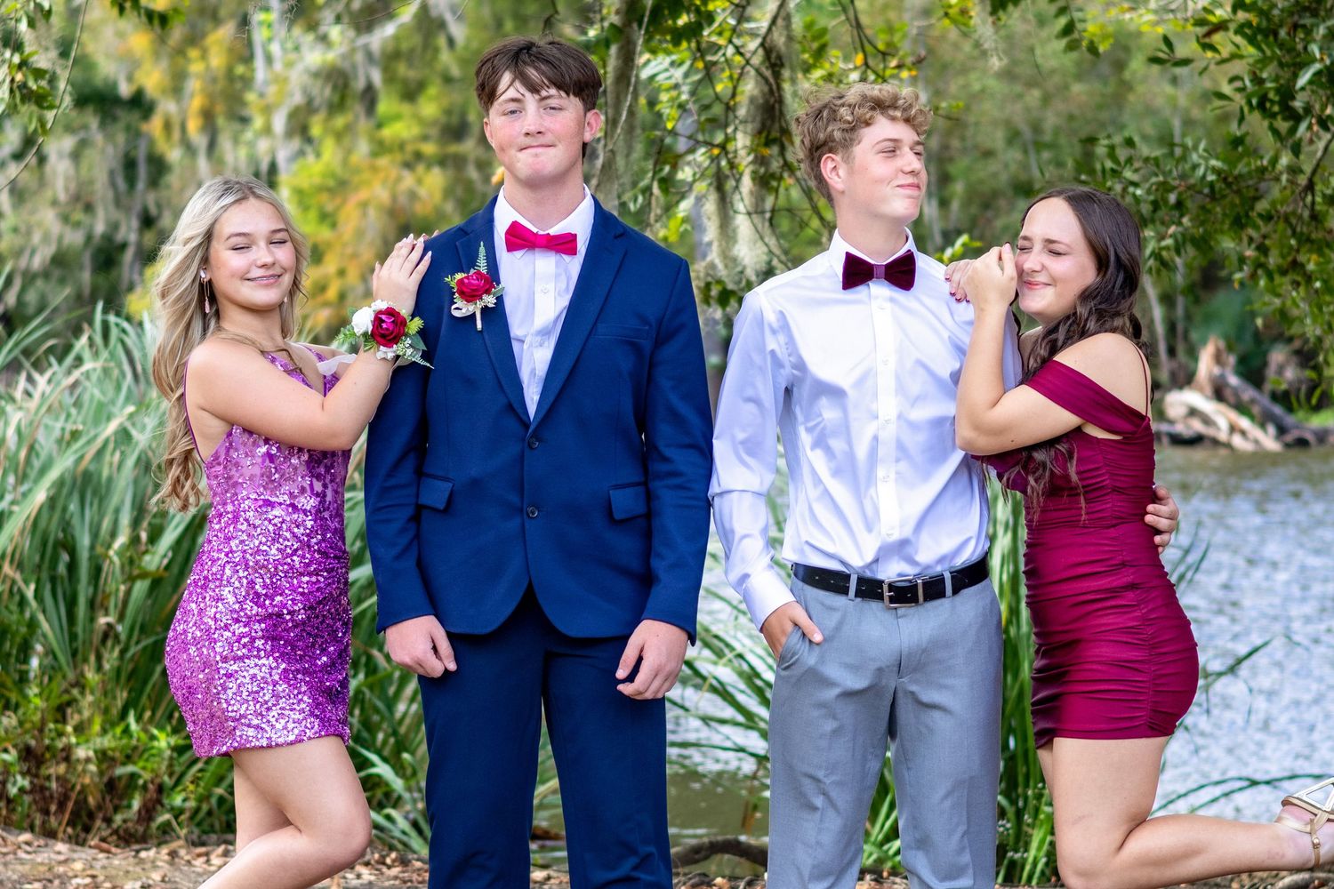 A group in formal attire poses together outdoors in a garden setting during a special event celebration.