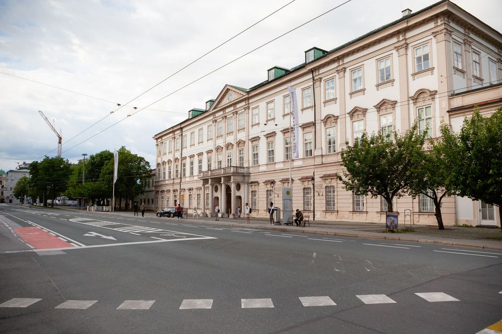 Historic building exterior with classical architecture and tree-lined street in an urban setting.