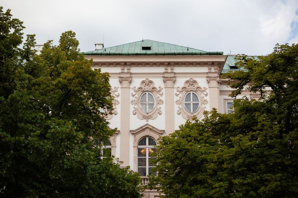 Exterior view of an elegant cream-colored historic building with ornate architecture and surrounding trees.