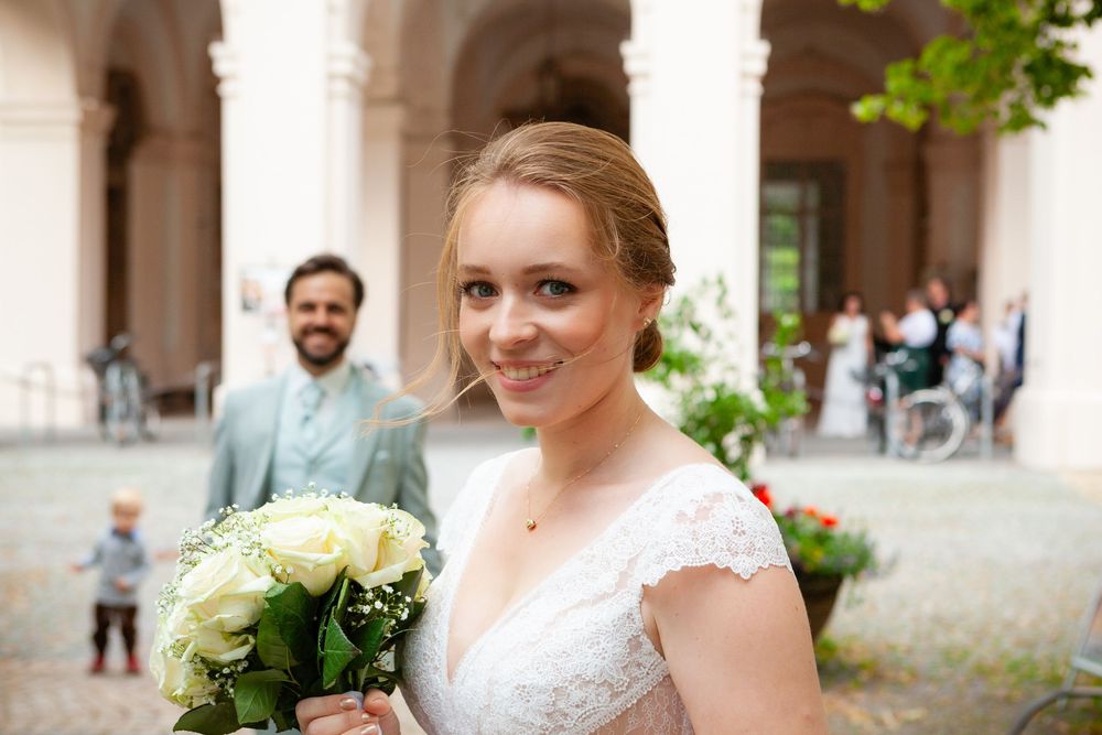 A wedding couple shares a tender moment in an elegant historic building interior.