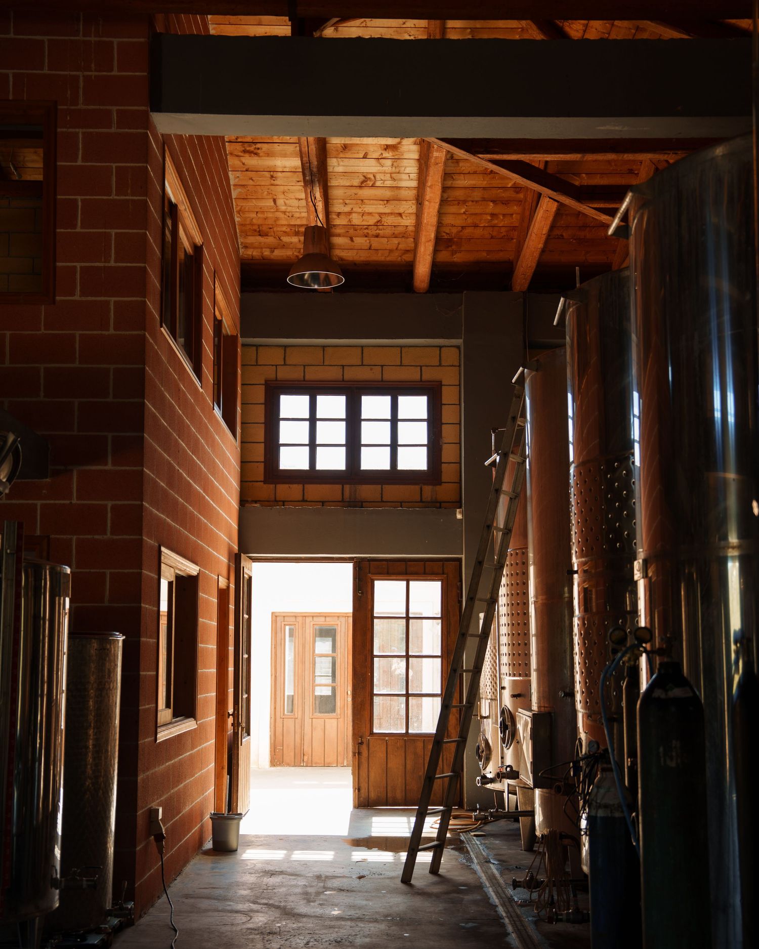 Sunlight streams through windows in a rustic wooden barn interior with exposed beams and support columns.