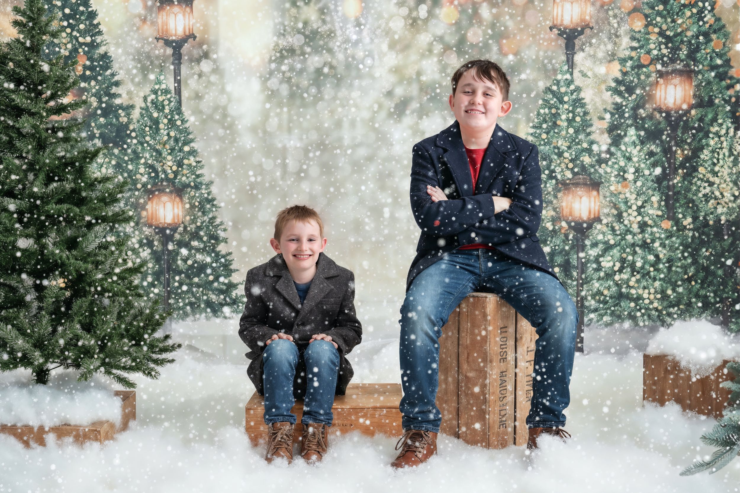 A winter scene with snow falling around evergreen trees and wooden crates creating a cozy holiday atmosphere.