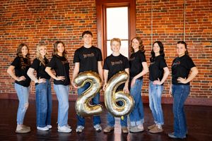A group in black shirts and jeans poses casually against a rustic brick wall in an artistic photo collage.