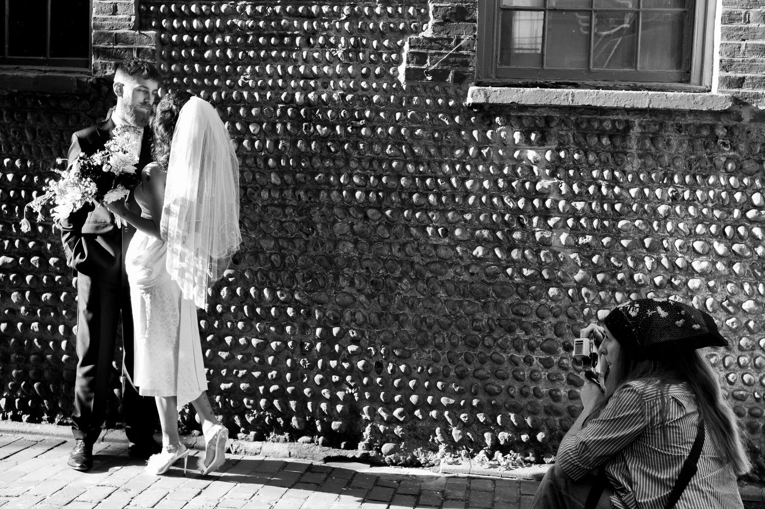 Monochrome photo strip showing a sequence of people walking in front of a brick wall with string lights overhead.