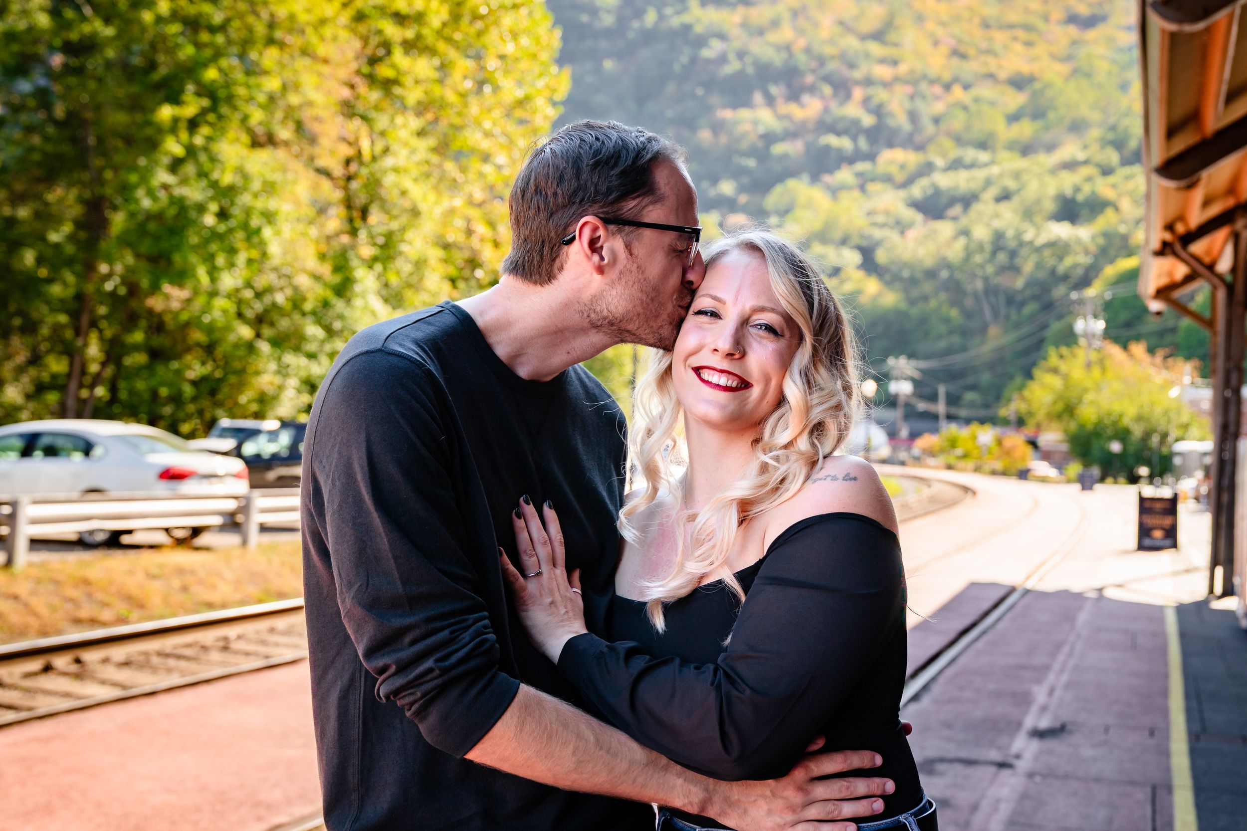 Couple enjoying a romantic moment at a scenic mountain train station in autumn.