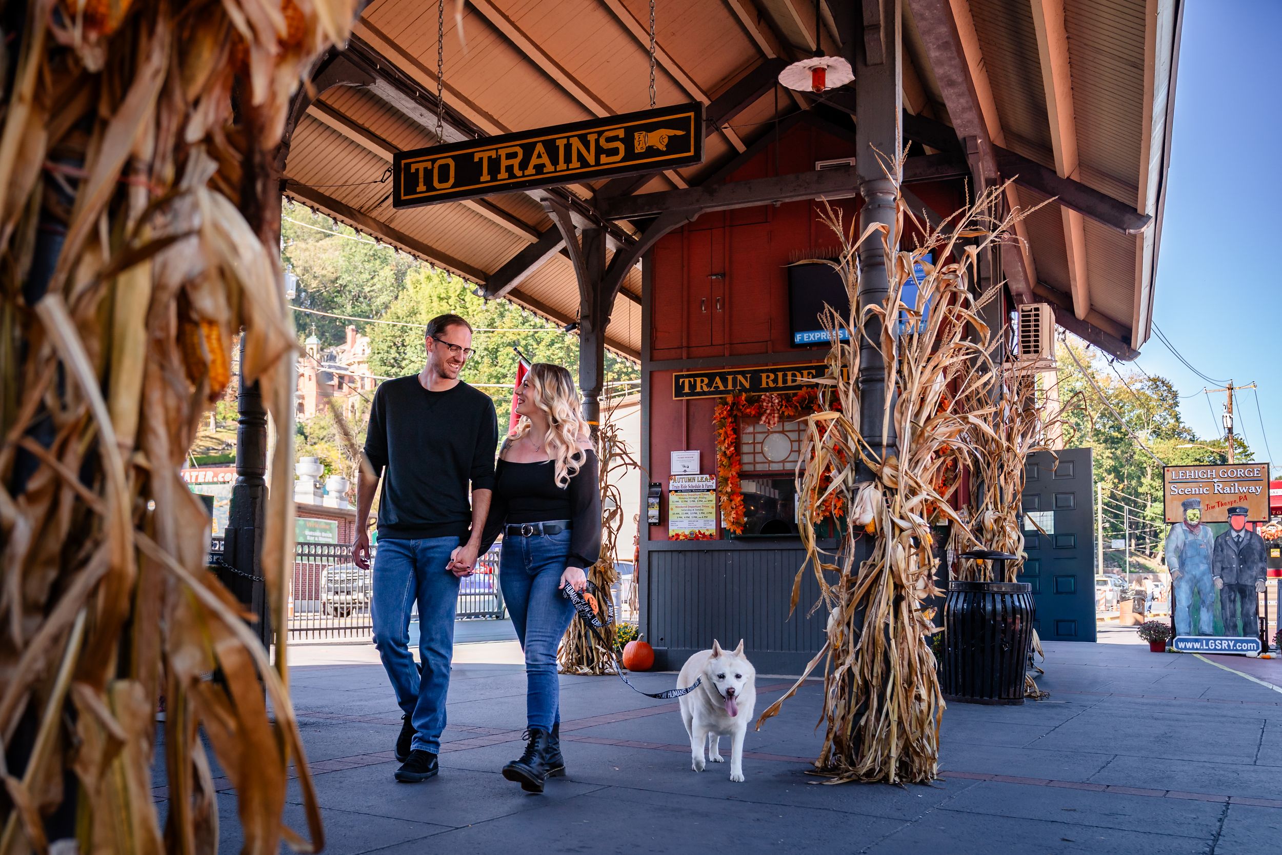 Train station platform decorated with autumn corn stalks and pumpkins.