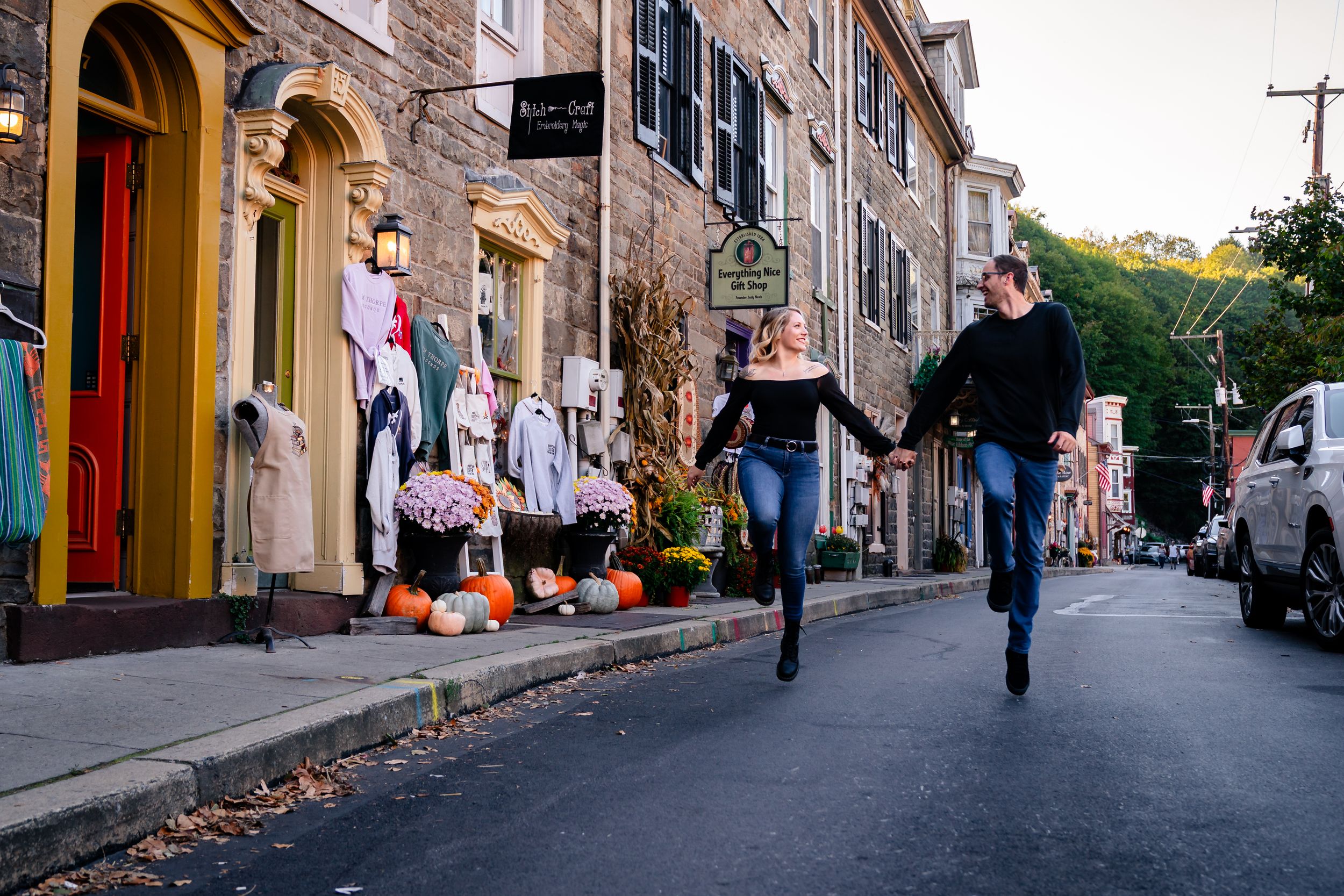 Charming historic street with stone buildings and pedestrians walking in autumn.