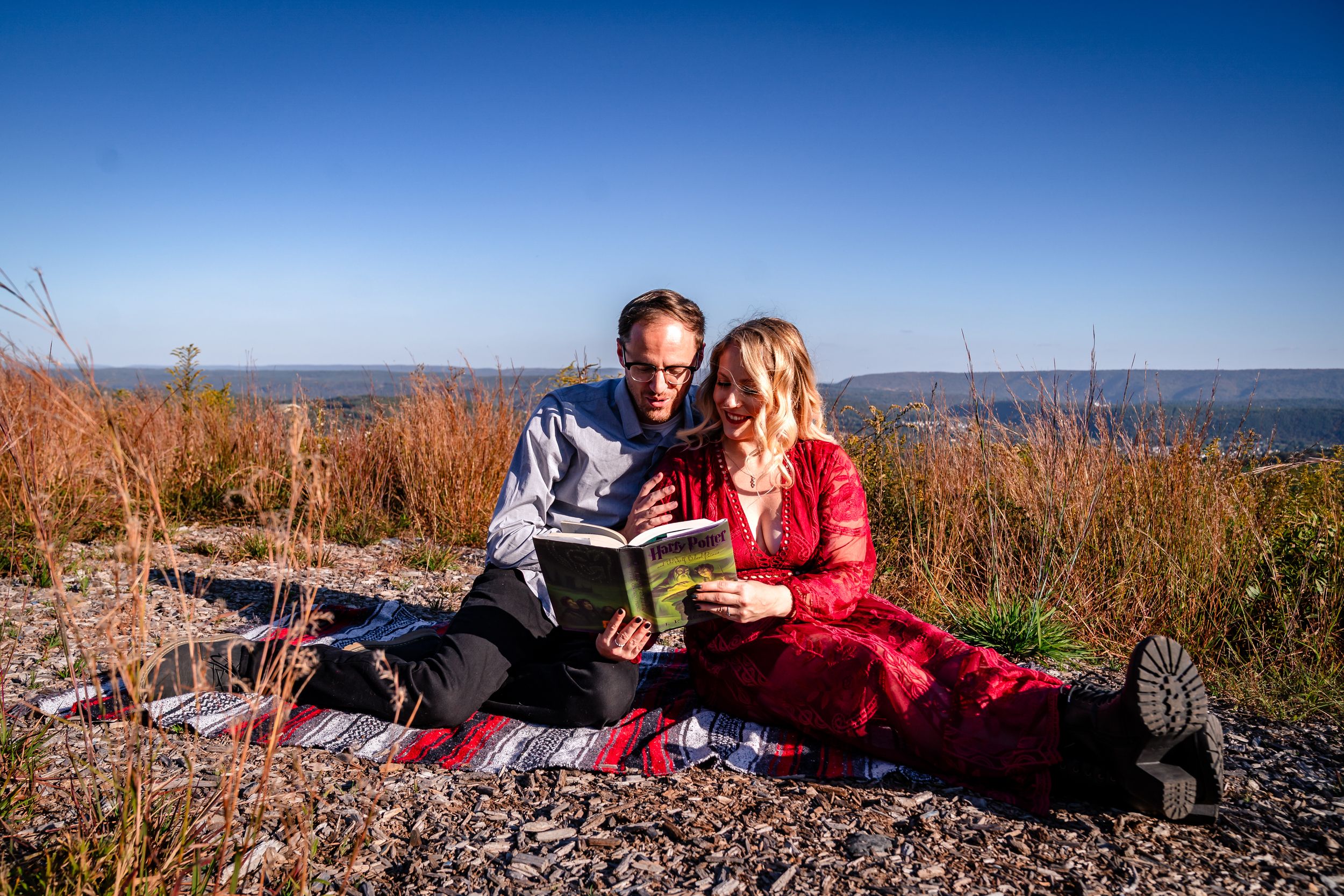 A romantic couple dances together on a mountain overlook with dramatic views of the landscape.
