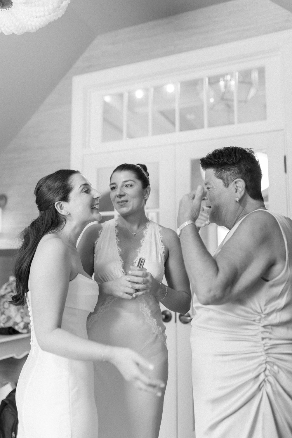 Candid black and white photo showing laughter during wedding preparations.